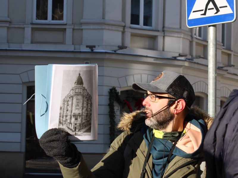 Dominik pokazuje grupie archiwalne zdjęcie kamienicy